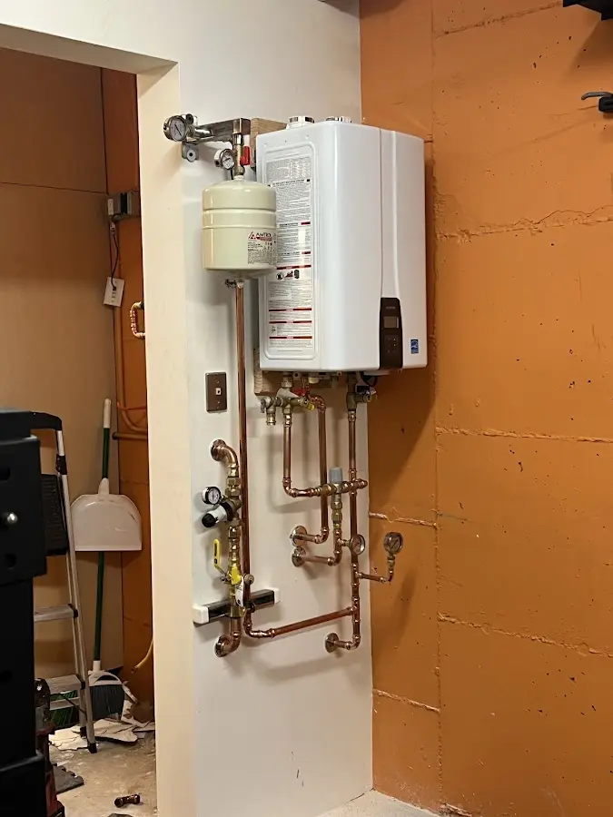 Plumbing technician inspecting water heater connections in Ames